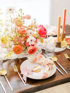 the table is set with plates, silverware and flowers