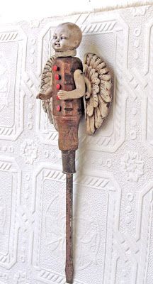 an old fashioned wall hook with a wooden angel holding a red ball in it's hand