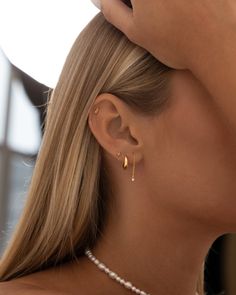 a woman wearing a pair of gold earrings