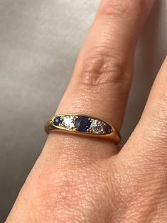 Beautiful Vintage English 18k Gold, Sapphires & Diamonds Ring. This ring is made in England and it comes with the makers initials and 18k hallmark. It features three beautiful blue sapphires and two diamonds. This makes a great stackable ring as well.  Weight: 3.95 grams Ring US size: 4.5 (resizable upon request) Very good antique conditions. Thank you for visiting Boudoir Vintage!   Please feel free to contact me for further information or photos.  I offer international shipping. Your item will be packed with extreme care and will be shipped within 3-5 working days. If you are dissatisfied with your item, please feel free to contact me and would be happy to assist.  If you are interested in paying in installments or reserve an item, please send me an inquiry. To continue visiting my shop, Elegant Three Stone Sapphire Ring In Yellow Gold, Elegant Three Stone Yellow Gold Sapphire Ring, Timeless Hallmarked Sapphire Ring, Timeless Yellow Gold Sapphire Wedding Jewelry, Formal Blue Rings With Single Cut Diamonds, Formal Blue Diamond Ring With Single Cut Diamonds, Formal Blue Ring With Single Cut Diamonds, Exquisite Brilliant Cut Sapphire Ring In Yellow Gold, Exquisite Yellow Gold Sapphire Ring With Brilliant Cut