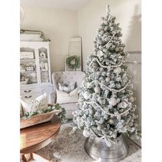 a white christmas tree sitting on top of a table next to a chair in a living room