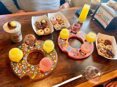 a wooden table topped with donuts, drinks and doughnuts on top of it