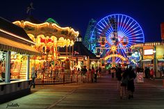 people are walking around an amusement park at night