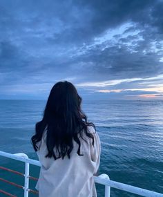 a woman looking out over the ocean at dusk