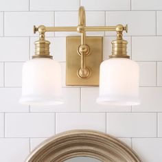 a bathroom light with two white shades on it and a mirror in front of it