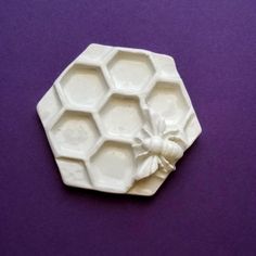 a mold that looks like hexagonals with a bow on the top, sitting on a purple surface