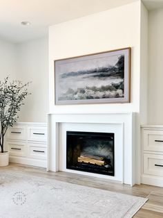 a living room with white furniture and a painting on the wall above the fire place