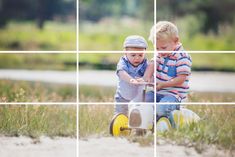 two young boys are playing with each other in the grass and one boy is on a tricycle