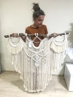 a woman is holding a large white macrame