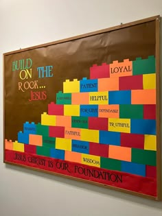 a bulletin board on the wall that says build on the rock jesus and is decorated with colorful blocks