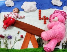 a baby laying next to a pink teddy bear