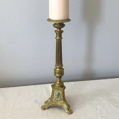 a white candle sitting on top of a metal stand