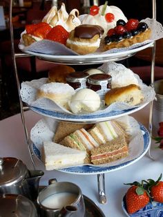 three tiered trays filled with pastries and desserts on top of a table