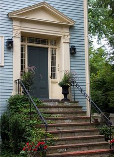 a blue house with steps leading up to the front door and flowers growing on either side