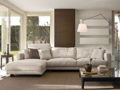 a living room with a sectional couch and coffee table in front of large windows that look out onto the backyard