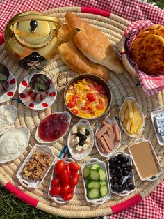 an assortment of food is arranged on a wicker platter with red and white checkered tablecloth