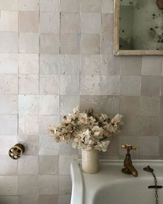 a white sink sitting under a bathroom mirror next to a wall mounted faucet