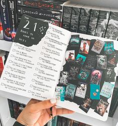 someone is holding up a book in front of a shelf full of books and dvds