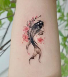 a woman's arm with a fish and flowers tattoo on the left side of her body