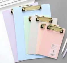 three colored clipboards are next to a keyboard