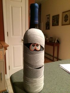 a wine bottle wrapped in bandages with eyes and nose on it's side, sitting on a table