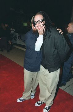 two men standing next to each other on a red carpet