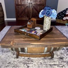 a coffee table with flowers and magazines on it in front of a wooden barn door