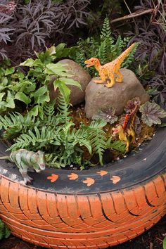 a toy dinosaur is sitting on top of an old tire and surrounded by plants in the garden