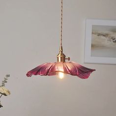 a pink flower sitting on top of a table next to a lamp