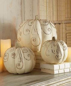 three white pumpkins sitting on top of a wooden table next to candles and books