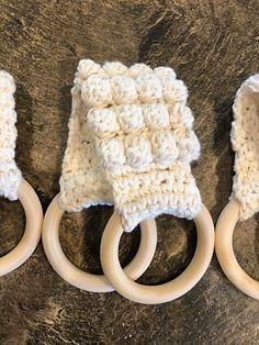 three crocheted rings are sitting next to each other on a table with two wooden handles