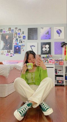 a woman sitting on the floor drinking from a cup