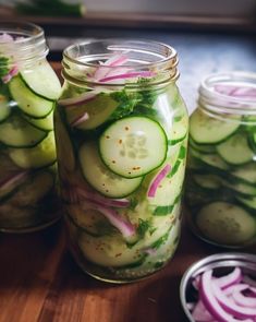 three jars filled with cucumbers and onions