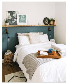 a bed with white linens and pillows in a bedroom next to a wooden shelf