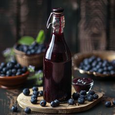 a glass bottle filled with blueberries sitting on top of a wooden table next to bowls of blueberries