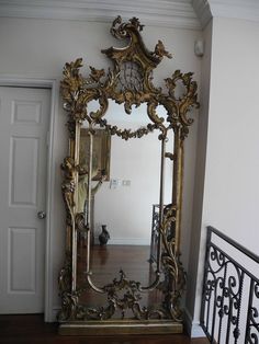 an ornate gold framed mirror sitting on top of a wooden floor next to a doorway