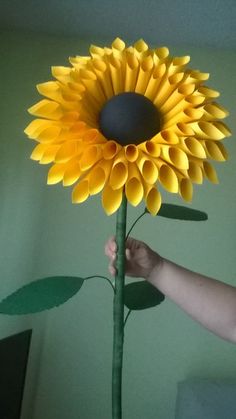 a person is holding a paper sunflower in their hand