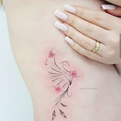 a woman's stomach with a bird tattoo on her left side ribcage