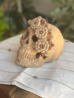 a wooden carved skull with flowers on it's head sitting on top of a table