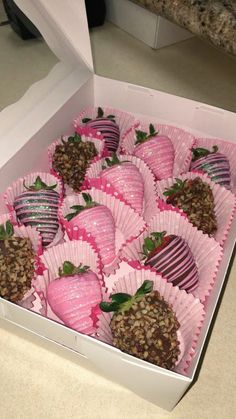 a box filled with chocolate covered strawberries on top of a table next to a counter