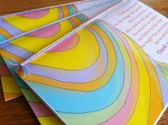 three colorful papers with ribbons tied to them sitting on a table next to each other