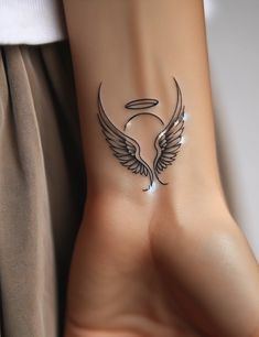 a woman's arm with an angel wing tattoo on it and the word love written in white ink