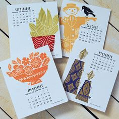 three calendars with different designs on them sitting on a wooden table next to each other