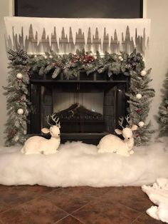 a fireplace decorated for christmas with fake snow and deers in front of the mantel