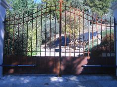 an iron gate is opened to reveal a driveway