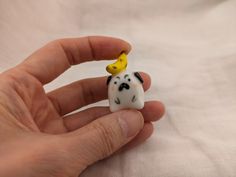 a hand holding a tiny toy dog with a banana on it's head