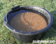 a large black bucket filled with lots of brown stuff sitting on top of green grass