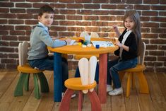 two children sitting at a table with paintbrushes