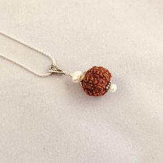 The elegant Shivam Rudraksha Pendant is an expression of the pure Divine nature of the Himalayan Rudraksha, which are the seed of a broad-leafed evergreen tree found mainly in the Himalayan foothills. It is believed that wearing these beads bring clarity, and create positive energy for the body, mind and soul. They are the eternal symbol of a Himalayan Yogi and coveted by Shiva Himself (Spirit). This pendant is accented with fresh water Pearls and Sterling Silver (925) findings. Each one comes w Traditional Brown Jewelry With Tiny Beads, Spiritual Silver Beads Mala Gift, Brown Spiritual Jewelry For Puja, Traditional Natural Jewelry For Rituals, Bohemian Brown Jewelry For Puja, Handmade Brown Jewelry For Puja, Spiritual Jewelry With Tiny Beads For Meditation, Spiritual Tiny Beads Jewelry For Festivals, Rudraksha Pendant