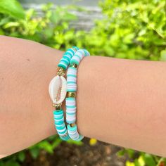 a woman's arm wearing two bracelets with shells and beads on the wrist